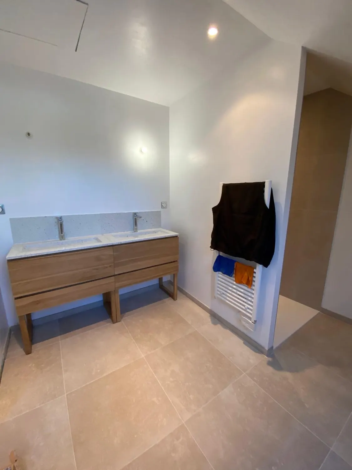 Grande salle de bain avec double vasque bois et sol travertin