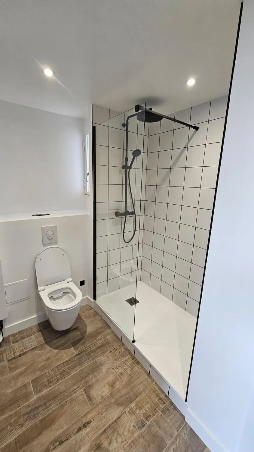 Salle d'eau avec WC suspendu et douche en carrelage métro blanc