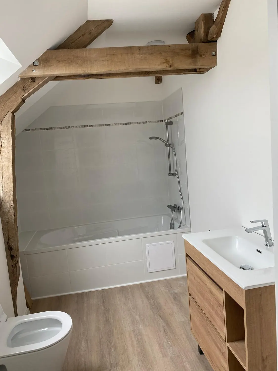 Salle de bain avec baignoire et douche sous poutres apparentes